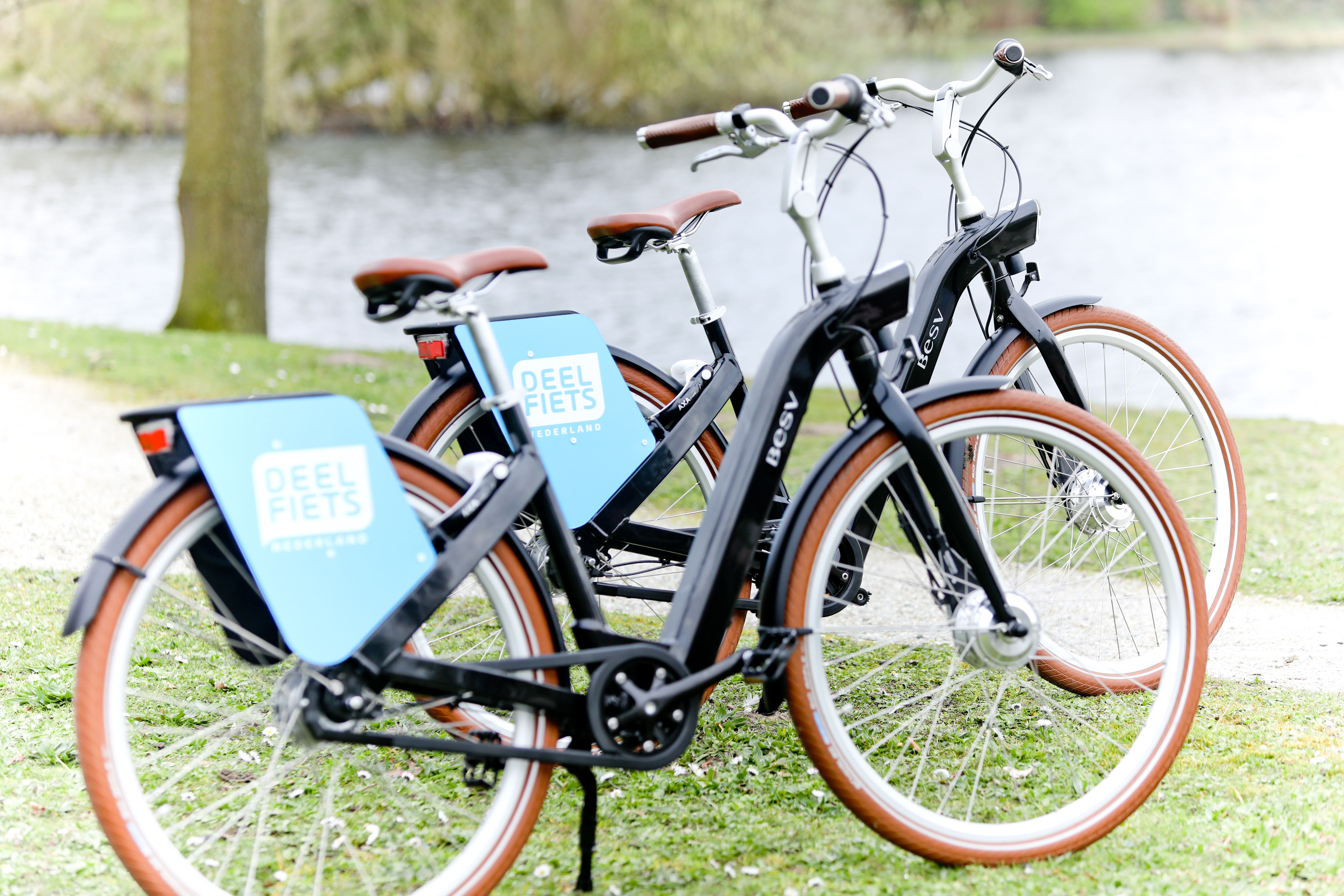 Twee deelfietsen van Deelfiets Nederland naast het water.