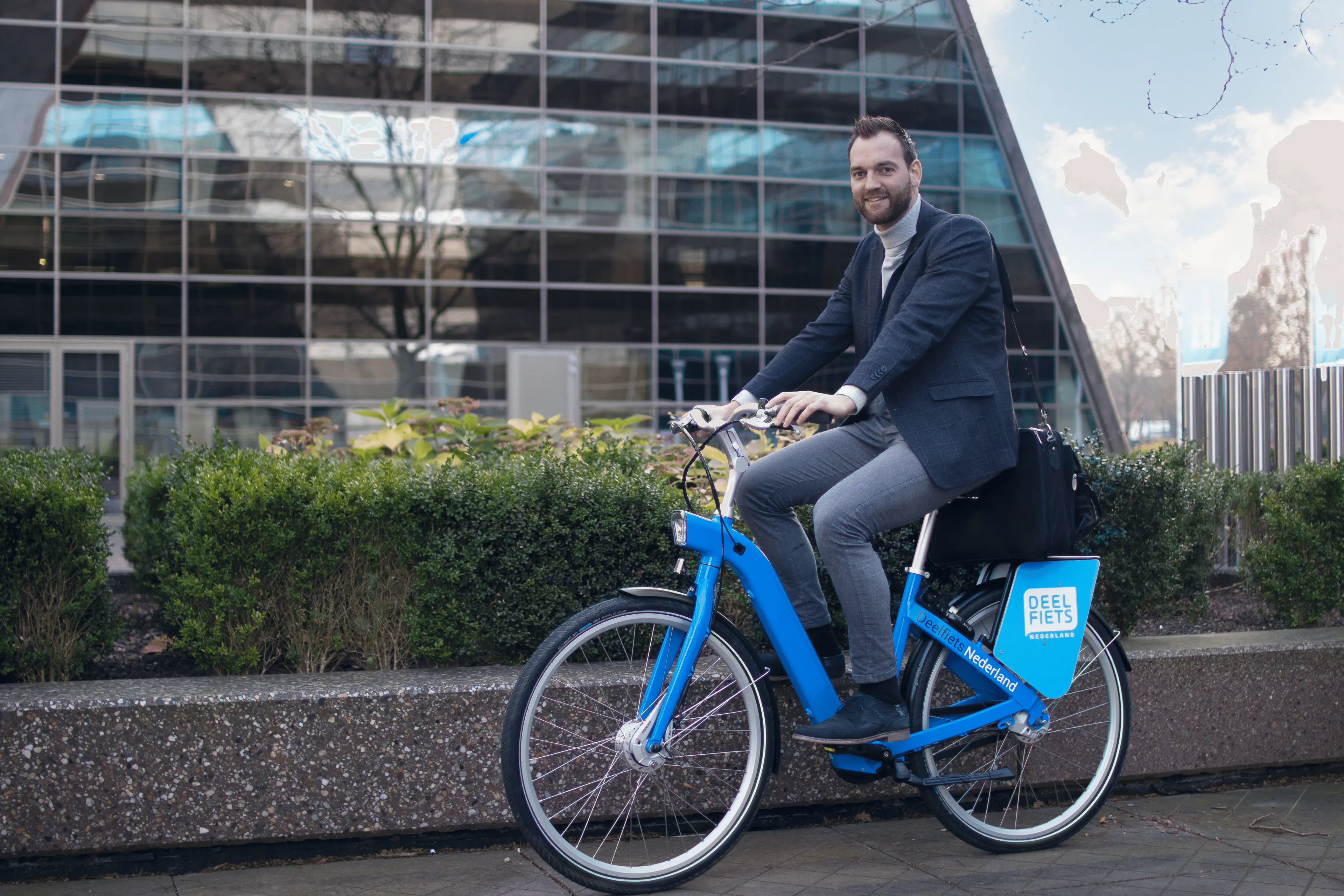 Een blije gebruiker op zijn zakelijke Deelfiets van Deelfiets Nederland.